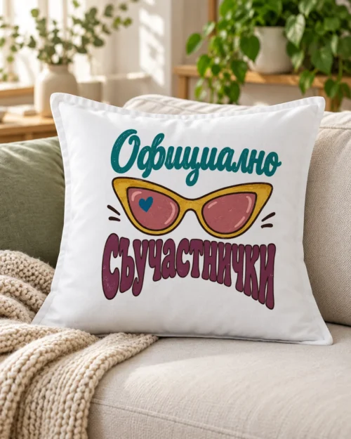 Бяла възглавница с жълти котешки слънчеви очила и надпис Официално съучастнички – на дивана
