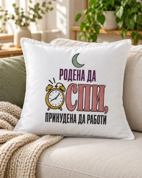 Бяла възглавница със звънящ будилник, полумесец и надпис Родена да спи – на дивана