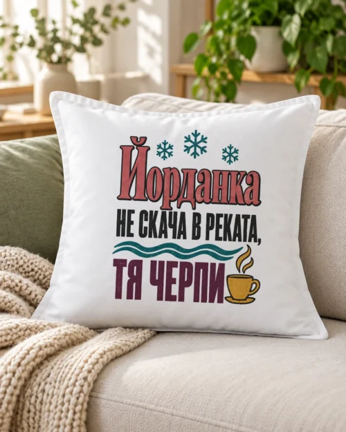 Бяла възглавница с шеговит надпис за Йордановден и име на именничката – на дивана