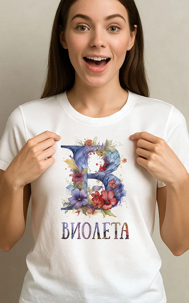 Усмихната жена показва бяла тениска с буква В от цветя и името Виолета
